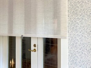 A door with a textured roller blind, a brass handle, and a glass panel with a dark reflective surface. - 6 Person Holiday Home in Hagby (Ljungbyholm)