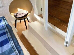 A room with a bed, a chair, and a small table. There is a door leading to an outdoor area with wooden flooring. - 6 Person Holiday Home in Hagby (Ljungbyholm)