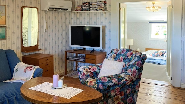 Ett vardagsrum med en tv, en blommönstrad fåtölj och en blå soffa.