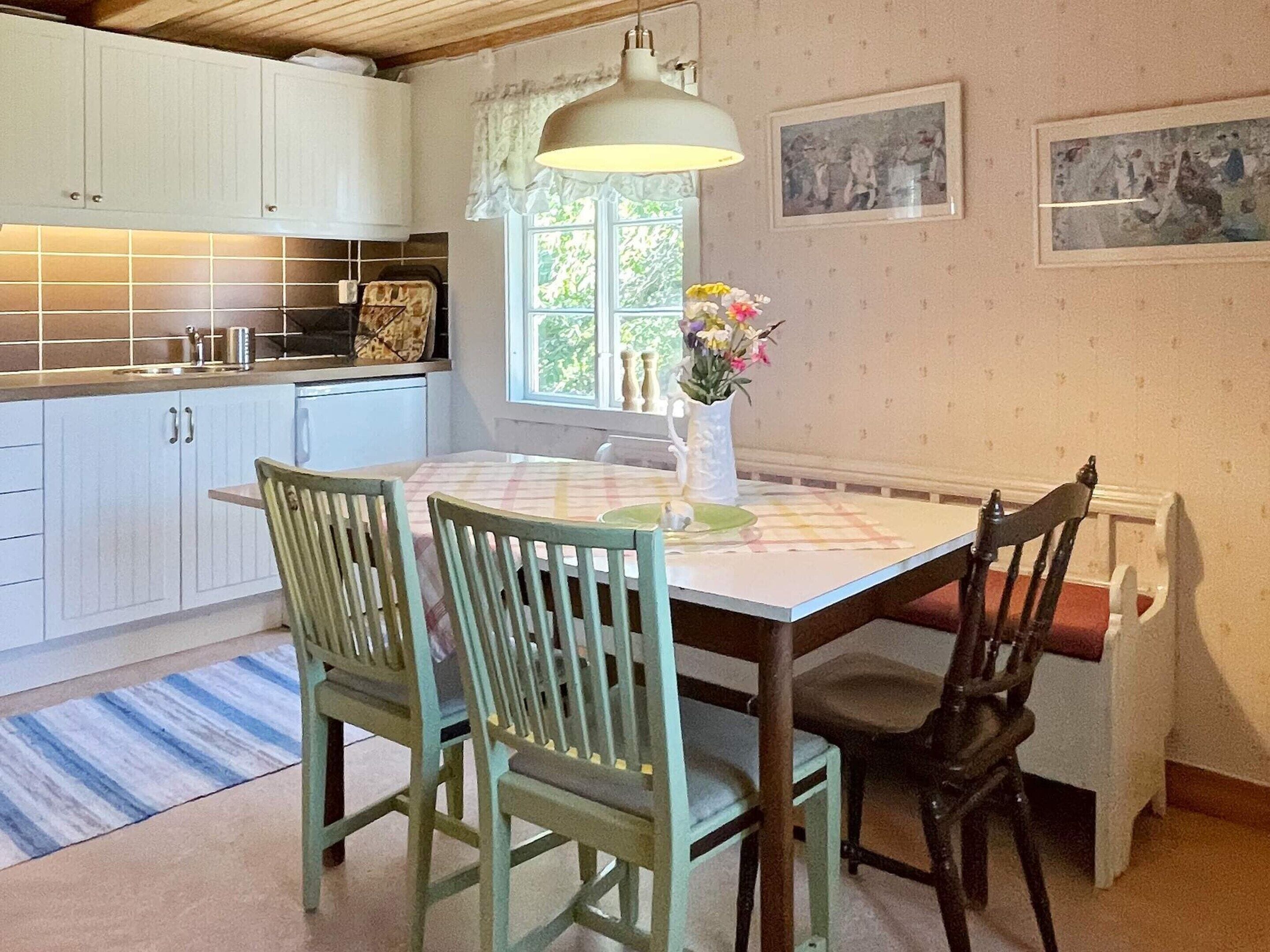 A kitchen with white cabinets, a dining table with a checkered tablecloth, and two chairs.