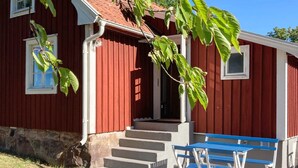 En röd träbyggnad med en veranda och blå bänkar.