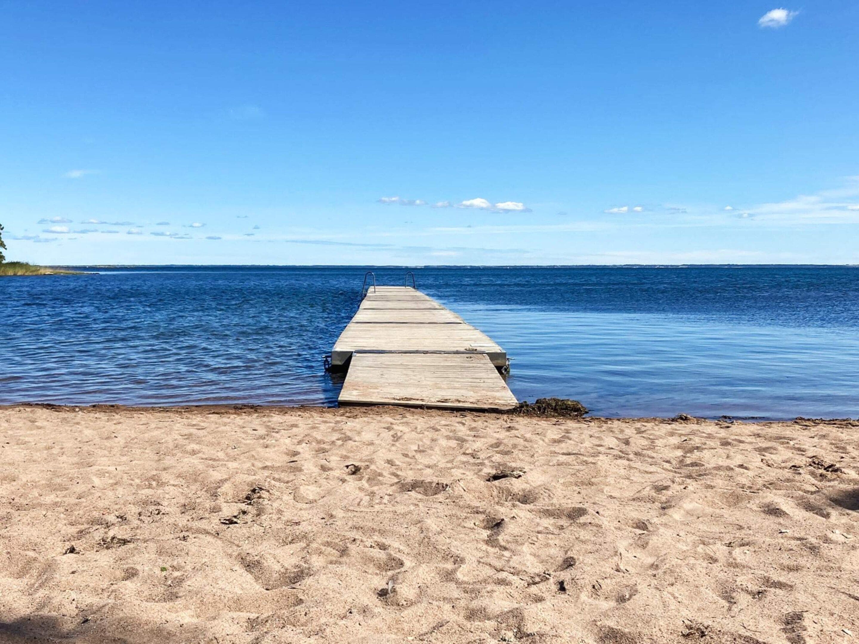A wooden pier extending into calm waters with a clear sky above.