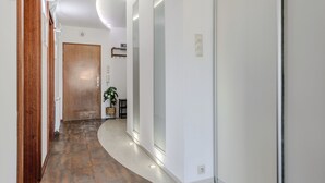 Un pasillo moderno con puerta de madera, una planta e iluminación empotrada.