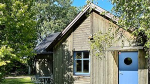 A wooden cabin with a blue door, a window, and a small porch with a table and chairs. - 6 Person Holiday Home in Borgholm (Borgholm)