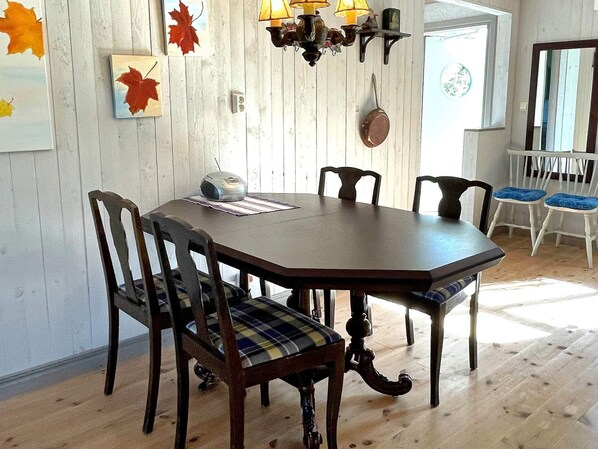 A dining area with a wooden table and chairs, a radio, and autumn leaf decorations on the wall. - 6 Person Holiday Home in Borgholm (Borgholm)