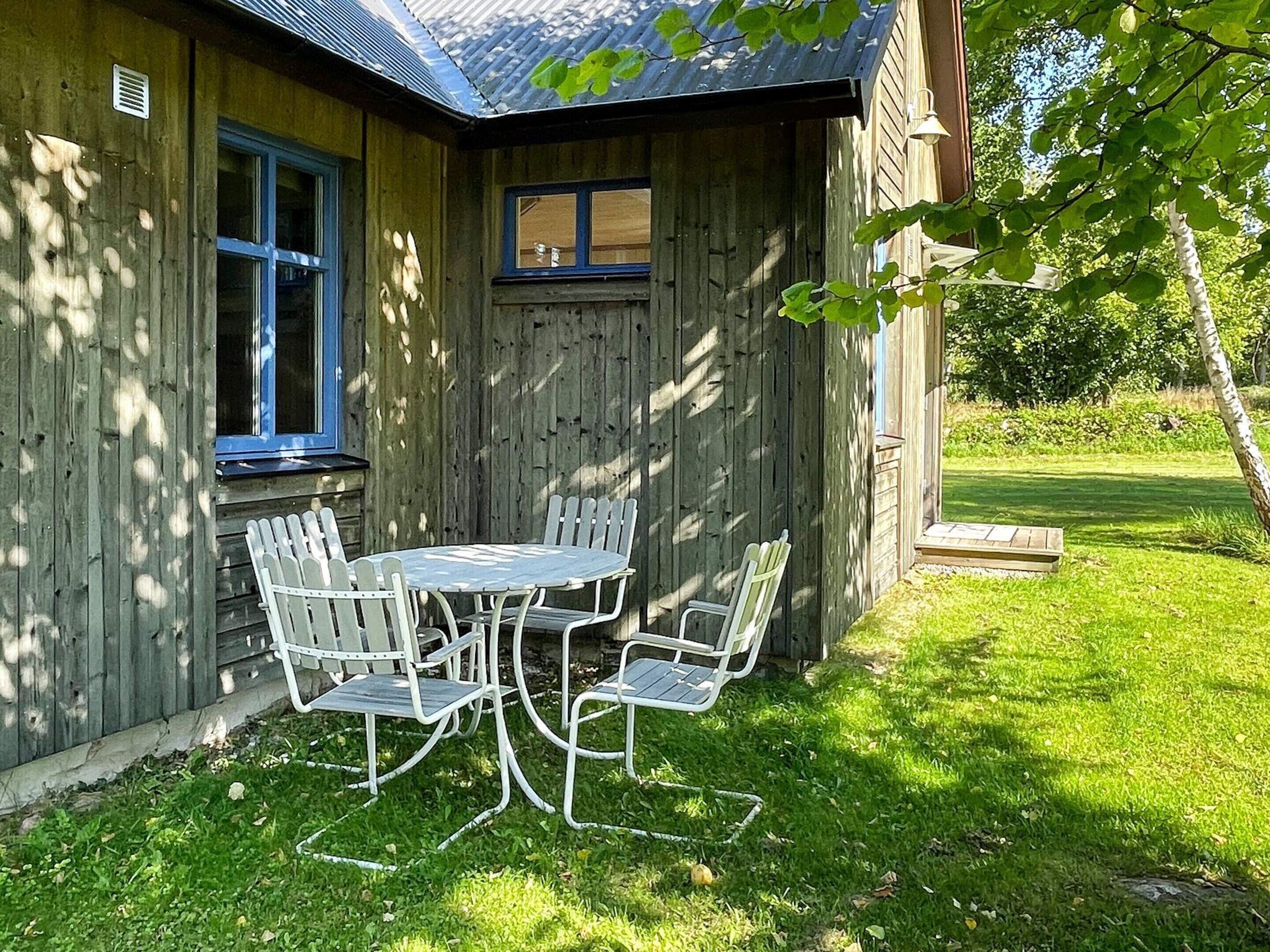 A wooden house with a covered patio and a table with chairs.
