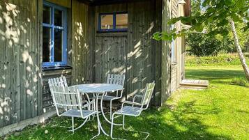 A wooden house with a covered patio and a table with chairs.
