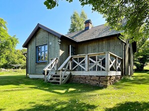 A wooden cabin with a stone foundation, a porch with a railing, and a chimney. - 6 Person Holiday Home in Borgholm (Borgholm)