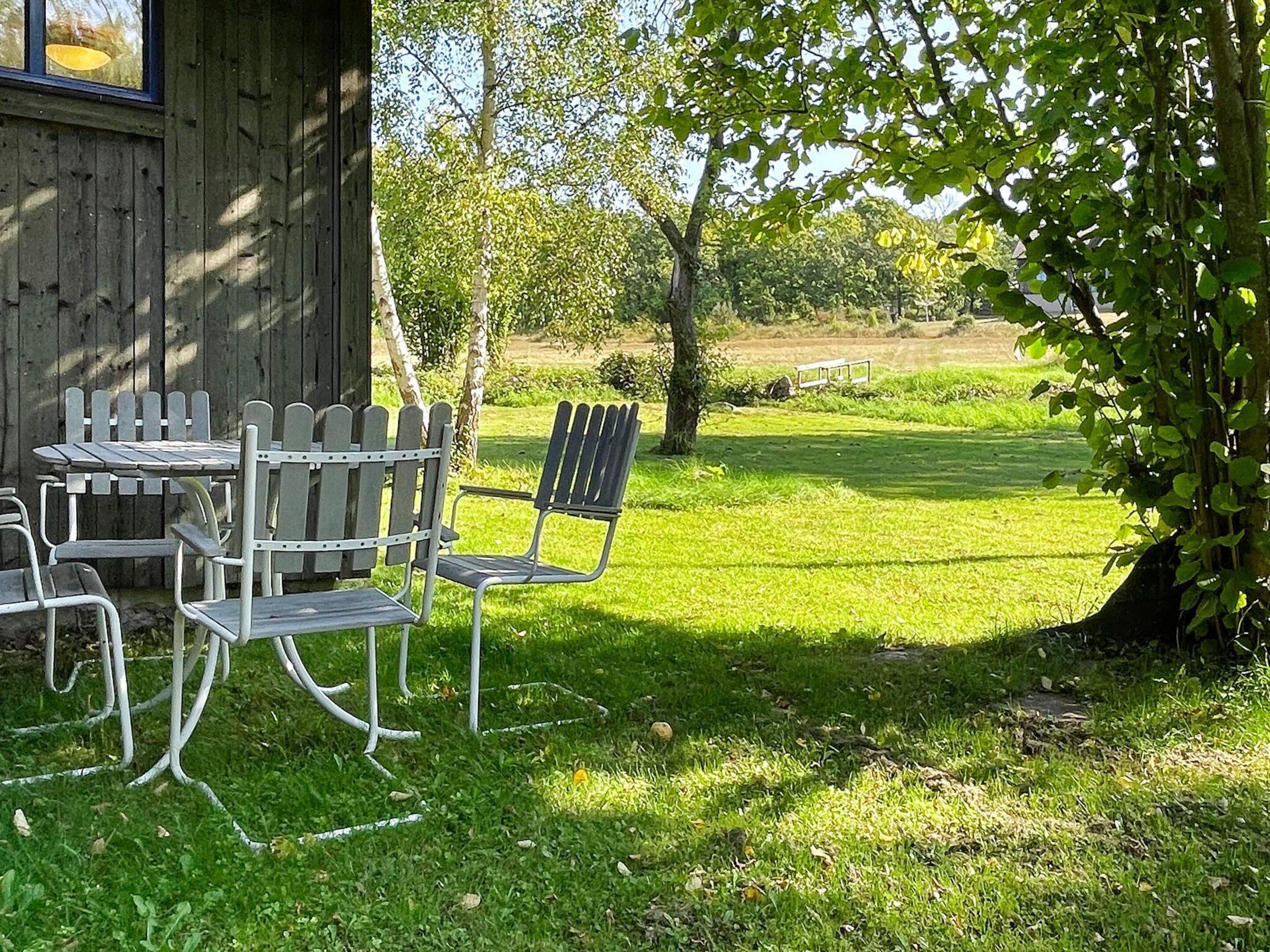 Un área de estar al aire libre con una mesa y sillas, rodeada de césped y árboles.