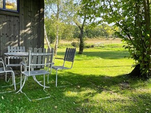 An outdoor seating area with a table and chairs, surrounded by a grassy lawn and trees. - 6 Person Holiday Home in Borgholm (Borgholm)