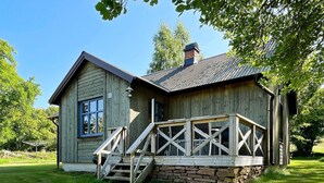 A wooden cabin with a stone foundation, a porch with wooden railings, and a chimney. - 6 Person Holiday Home in Borgholm (Borgholm)