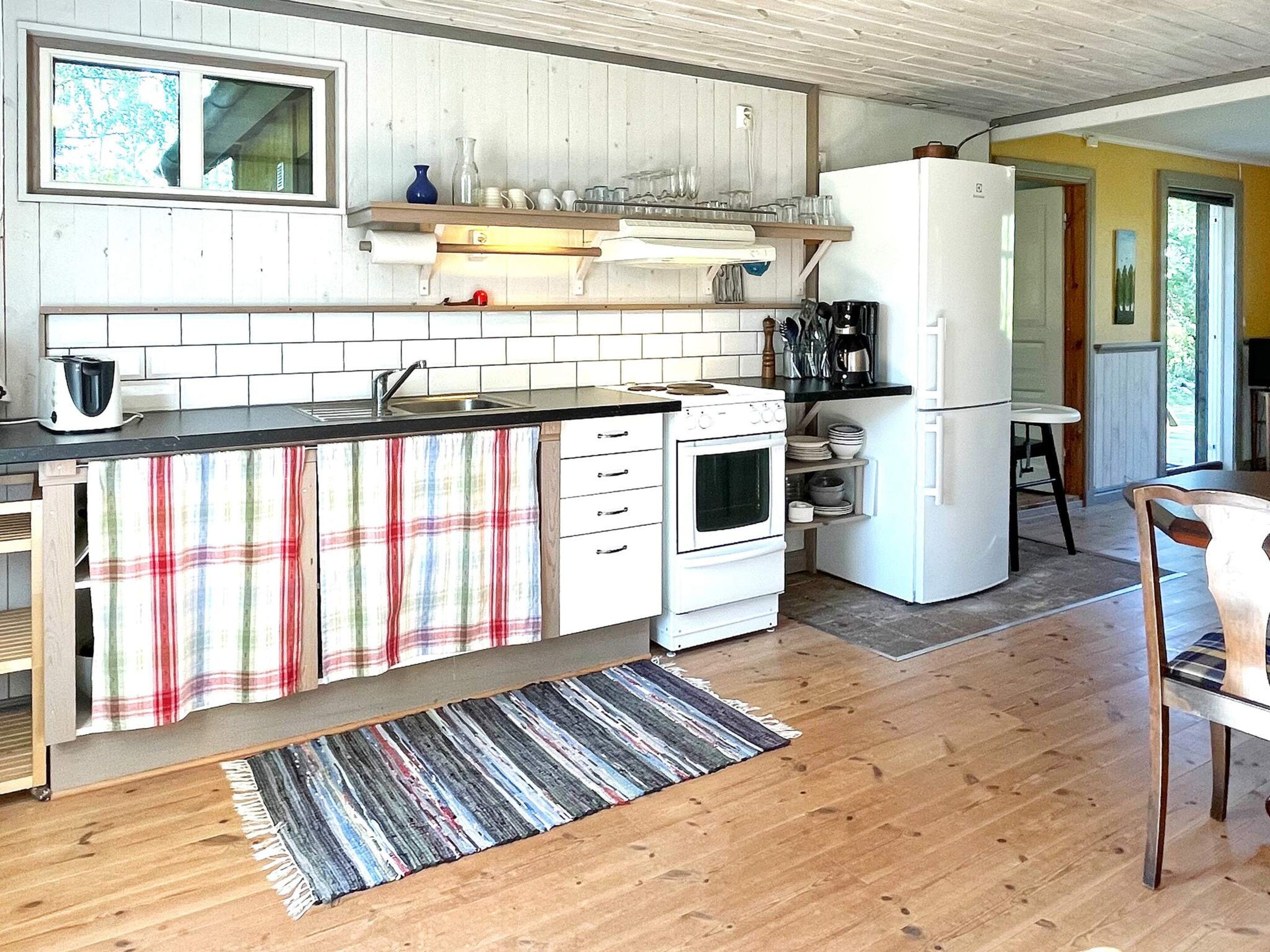 A kitchen with a wooden countertop, white cabinets, a stove, and a refrigerator.