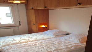 A bedroom with a large bed, wooden headboard, and a wall-mounted light fixture. - Apartment in Veysonnaz Near Ski Gondola (Veysonnaz)