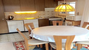 A compact kitchen with wooden cabinets, a white countertop, a stove, a microwave, and a hanging light fixture. - Apartment in Veysonnaz Near Ski Gondola (Veysonnaz)