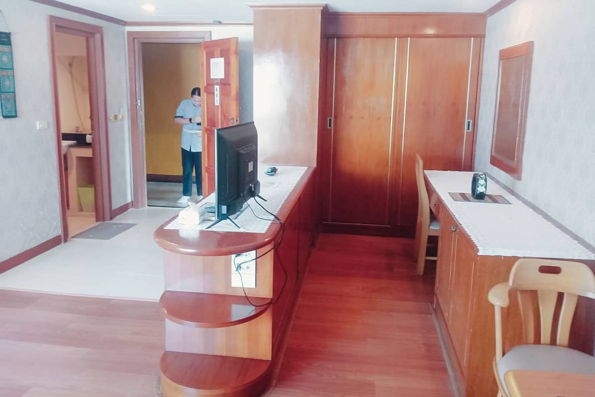 A hotel room with a wooden desk, a television, a chair, and a wardrobe.