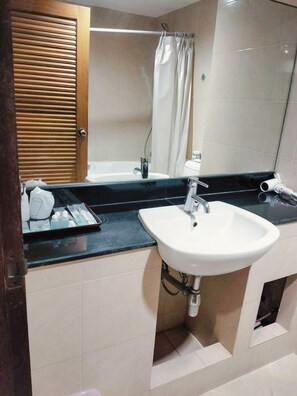 A bathroom with a sink, mirror, and shower. - Antai Holiday Hotel (Pattaya)