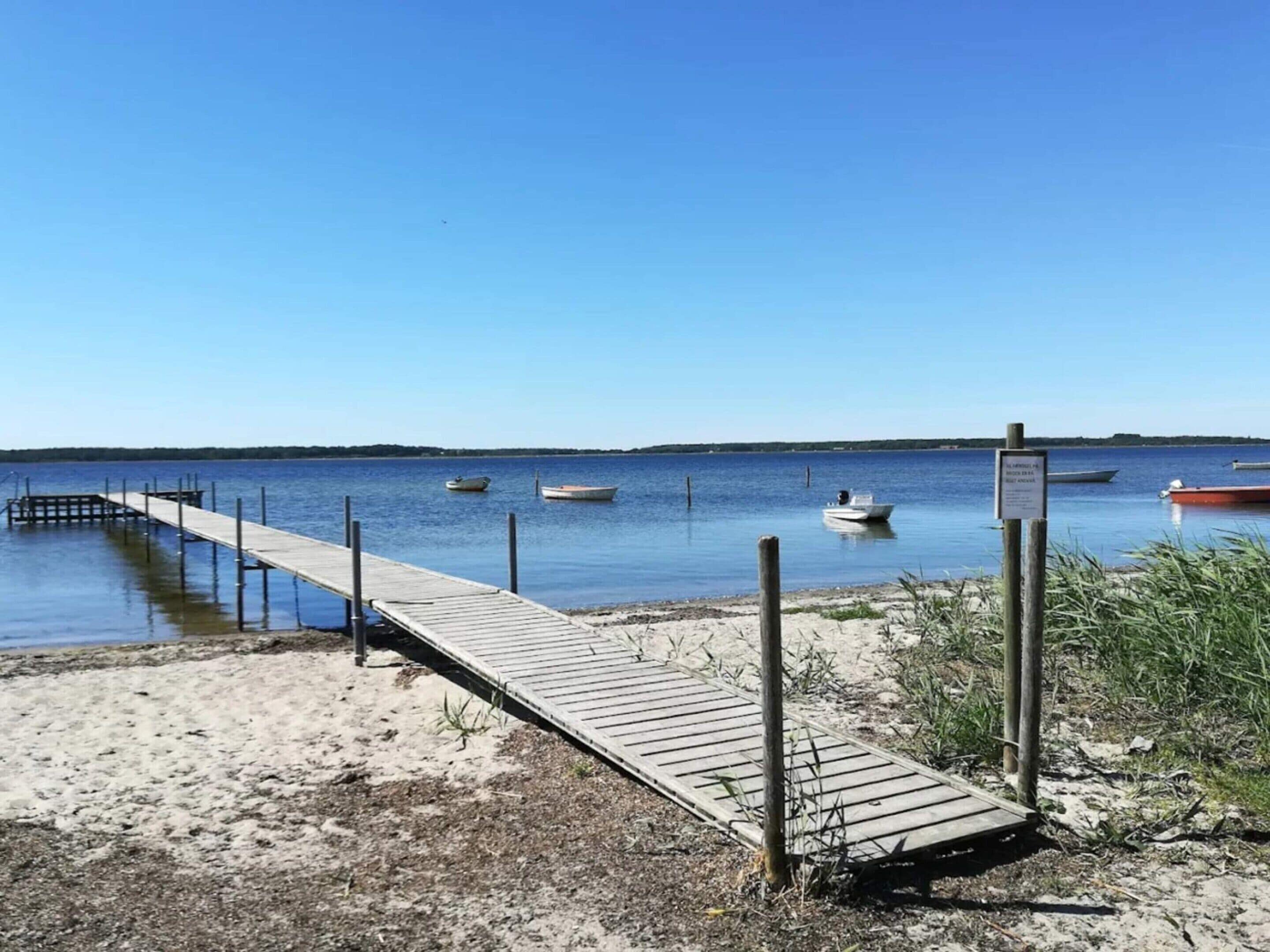 Une jetée en bois s’étendant dans une étendue d’eau calme, avec plusieurs bateaux amarrés à proximité.