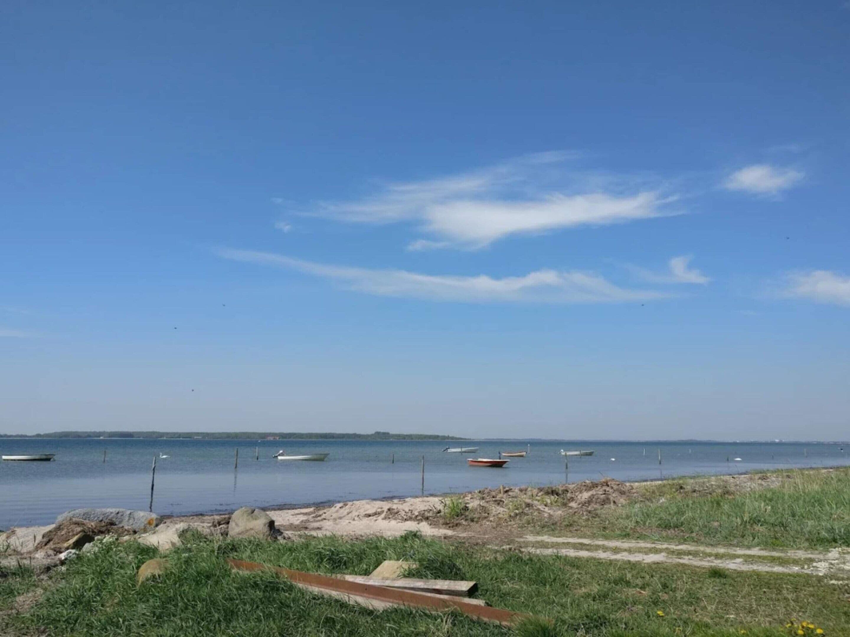 Une plage avec des bateaux, un rivage sablonneux et un ciel dégagé.