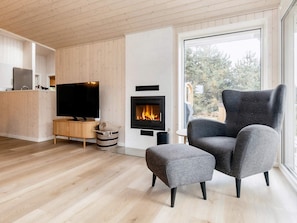 A modern living room with a television, a fireplace, and a large window.