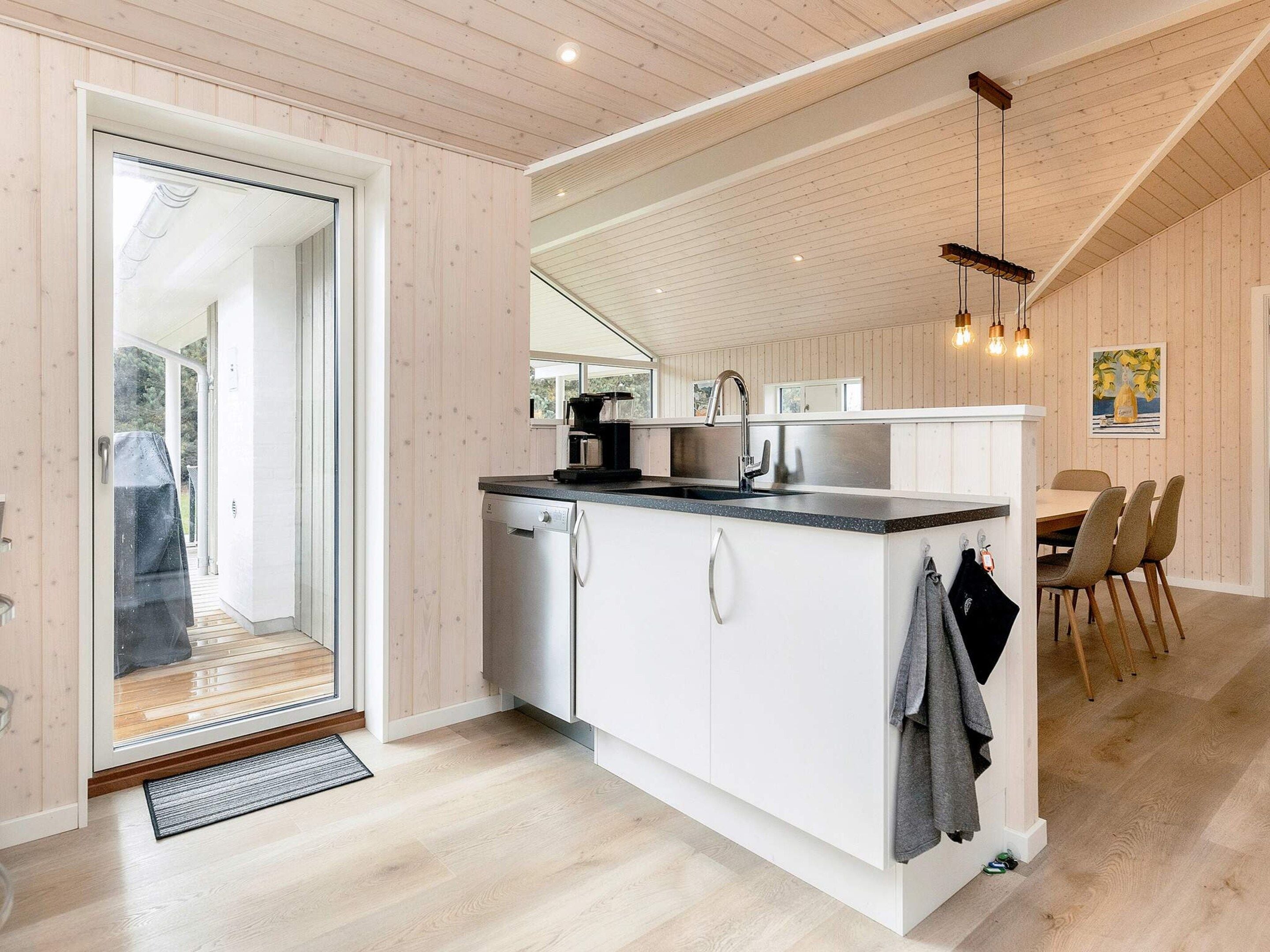 Een moderne keuken met een vaatwasser, een spoelbak en een eethoek met stoelen.