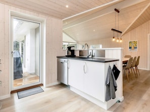 A modern kitchen with a dishwasher, a sink, and a dining area with chairs.