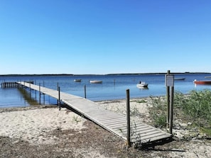 A wooden dock extending into calm water with several boats anchored nearby.