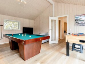 A room with a pool table, a foosball table, a television, and a window with a view of trees. - 5 Star Holiday Home in Vaeggerlose (Vaeggerlose)