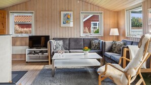 A cozy living room with a high ceiling, wooden walls, a sofa set, a coffee table, and a TV. - "Bjarni" - 175m from the sea by Interhome (Malling)