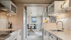 A modern kitchen with white cabinetry, a built-in oven, a sink, and a dining area with a table and chairs. - "Bjarni" - 175m from the sea by Interhome (Malling)
