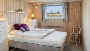 A bedroom with a bed, a chair, a window, and wooden walls. - "Bjarni" - 175m from the sea by Interhome (Malling)