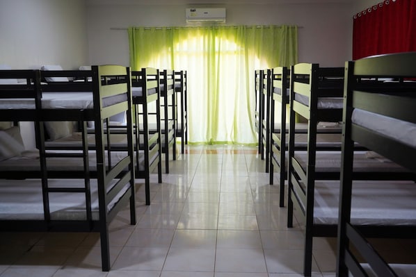 A room with bunk beds arranged in two rows, a tiled floor, and a window with green curtains. - Hidden Valley Mountain and Wavepool Resort (Pinamungajan)