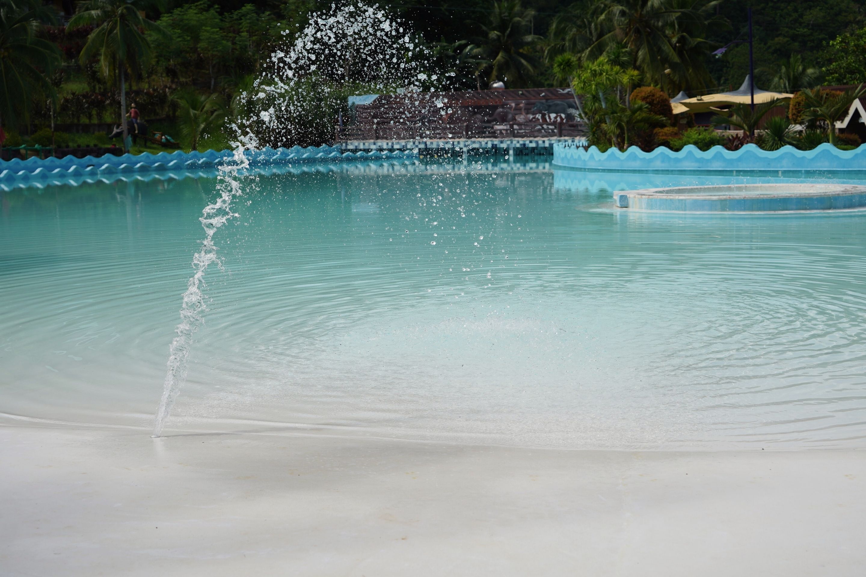 A pool with clear water and a splash of water in the center.