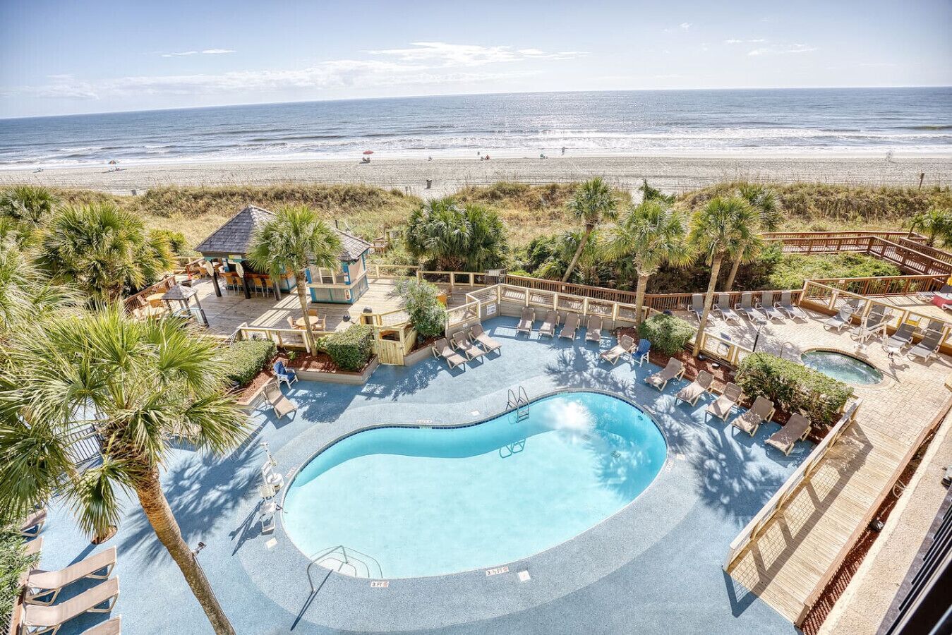A pool area with lounge chairs and a view of the beach.