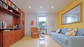 Ein Wohnzimmer mit Bücherregal, einer Couch, einem Sessel und einem Couchtisch.