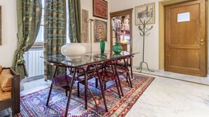 Un comedor con mesa de vidrio y sillas de madera, alfombra estampada y una puerta de madera.