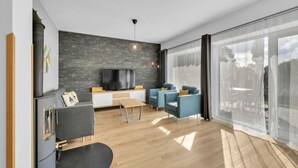 Een moderne woonkamer met een stenen muur, een flatscreen televisie, een bank, een salontafel en een groot raam met uitzicht.