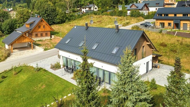 Een modern huis met een schuin dak, grote ramen en een verzorgd gazon.