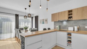 Een moderne keuken met witte kastjes, een houten aanrecht en hangende lampen.