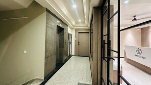 Ein Hotelgang mit Marmorwand, einer Rezeption und einer Tür mit der Aufschrift "Lift 2".