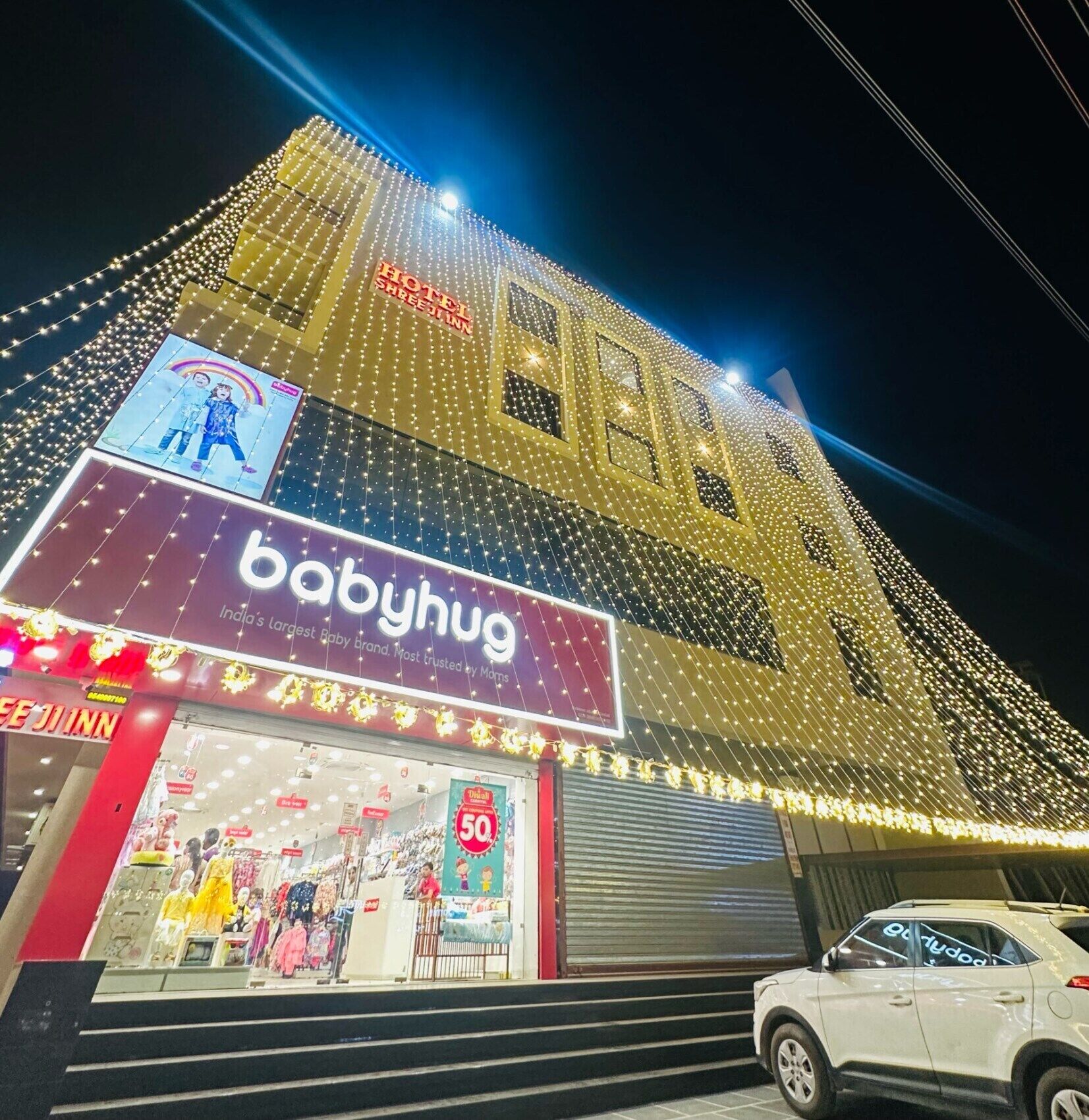 A building with a Babyhug store on the ground floor, featuring a large sign and a display window with children's clothing.