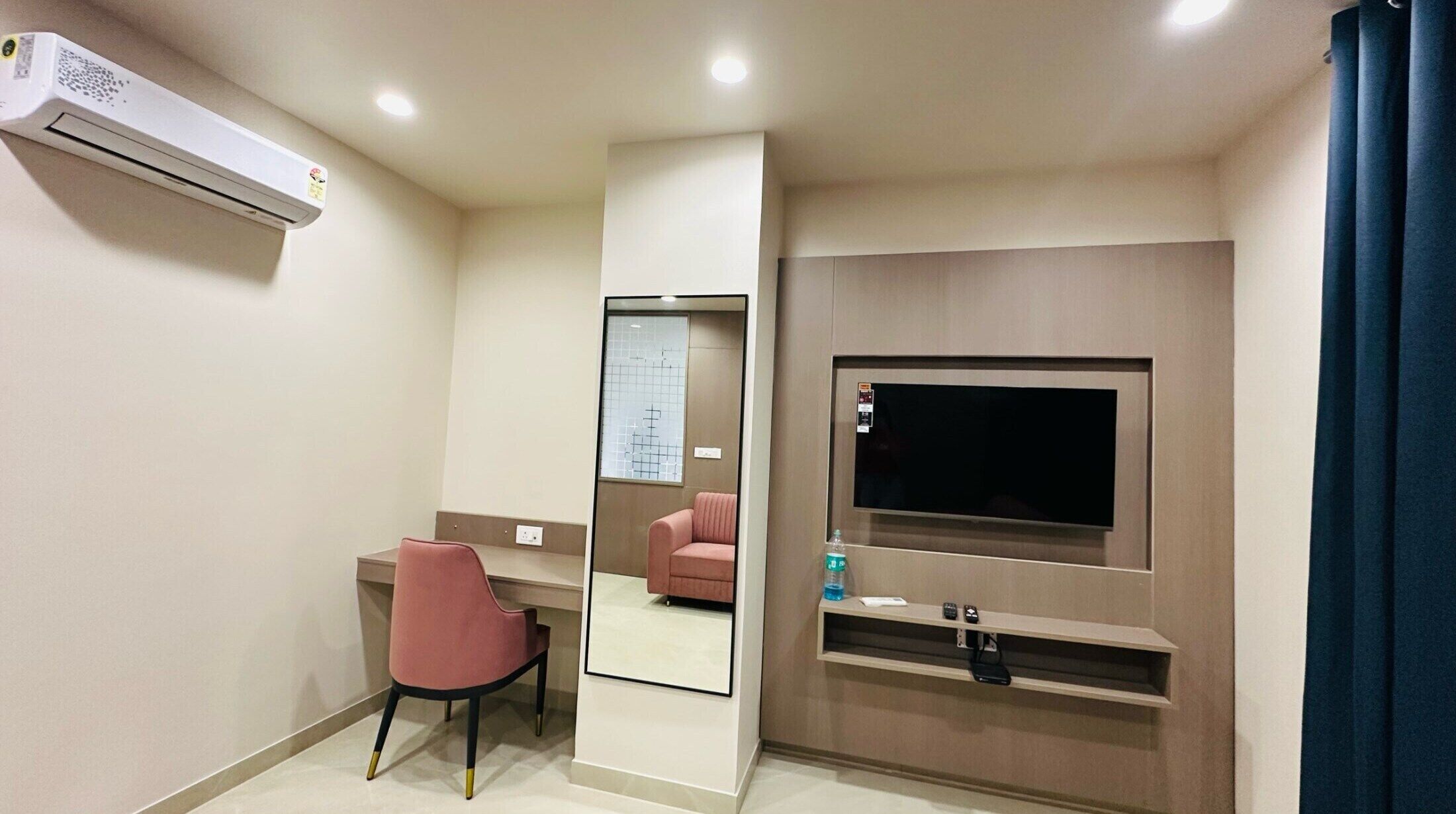 Habitació d'hotel amb televisió de pantalla plana penjada a la paret, una taula amb una cadira i un aire condicionat.