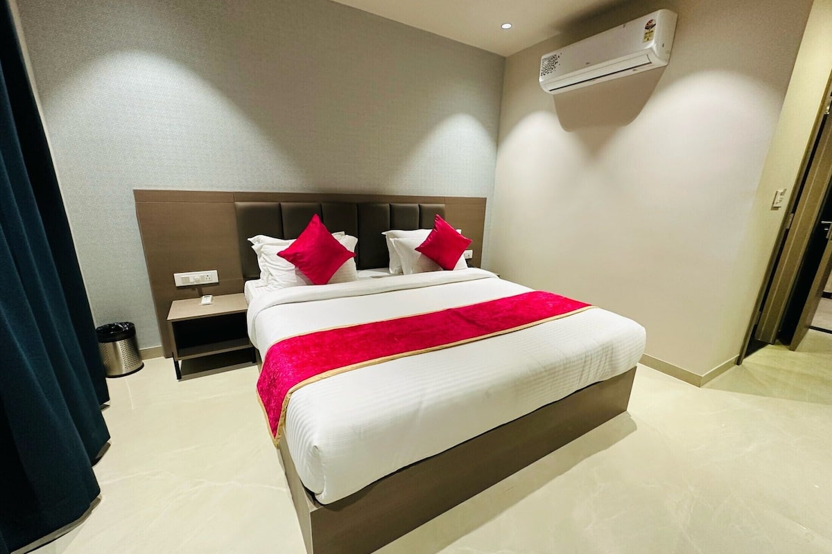 Une chambre d’hôtel avec un lit, une table de chevet, une poubelle et un appareil de climatisation fixé au mur.