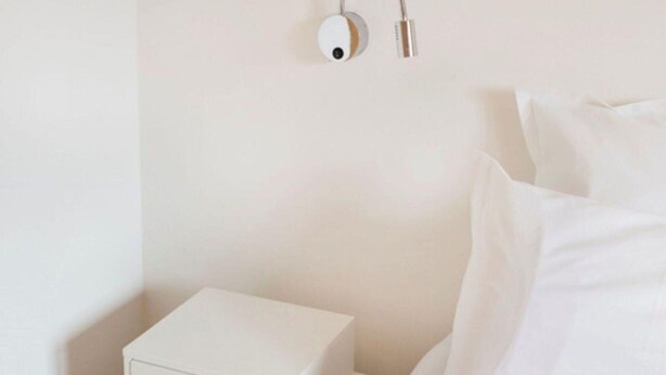 A neatly made bed with white linens, a small bedside table with a drawer, and a wall-mounted light fixture. - Luxury Chalet With Sauna and Garden (Vex)