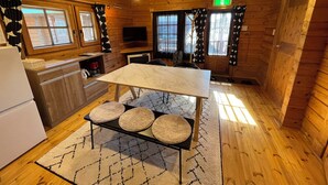 L’intérieur d’une cabane en bois comprend un coin cuisine, une table à manger avec des tabourets et un téléviseur.