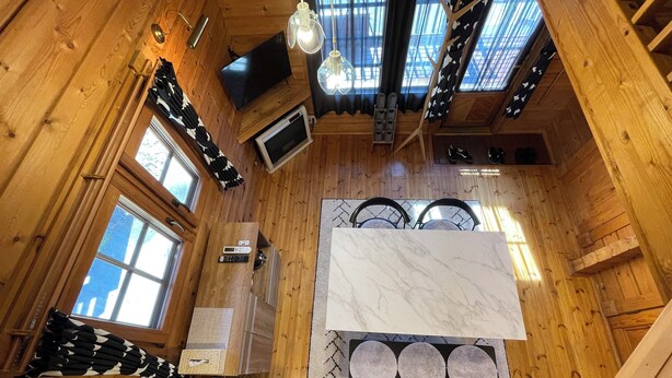 L’intérieur d’une cabane en bois comprend un espace cuisine équipé d’une cuisinière, d’un évier et d’une grande fenêtre.