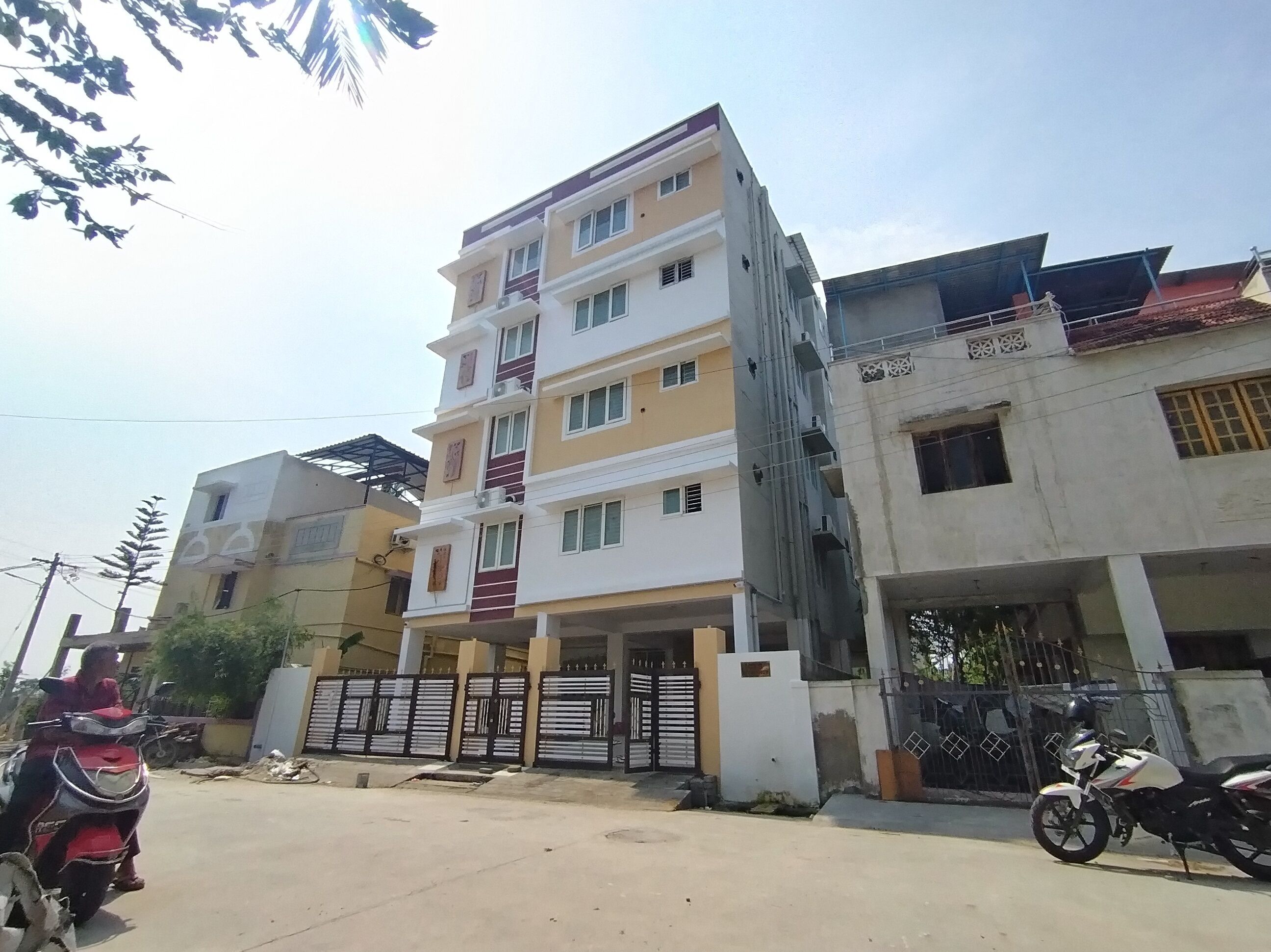 A multi-story residential building with a gated entrance and a parked motorcycle.