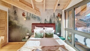 A bedroom with a bed, pillows, a headboard, a window, and a wall with a forest mural. - Le Grand Cerf - appartement 8 pers - proche centre (Les Gets)
