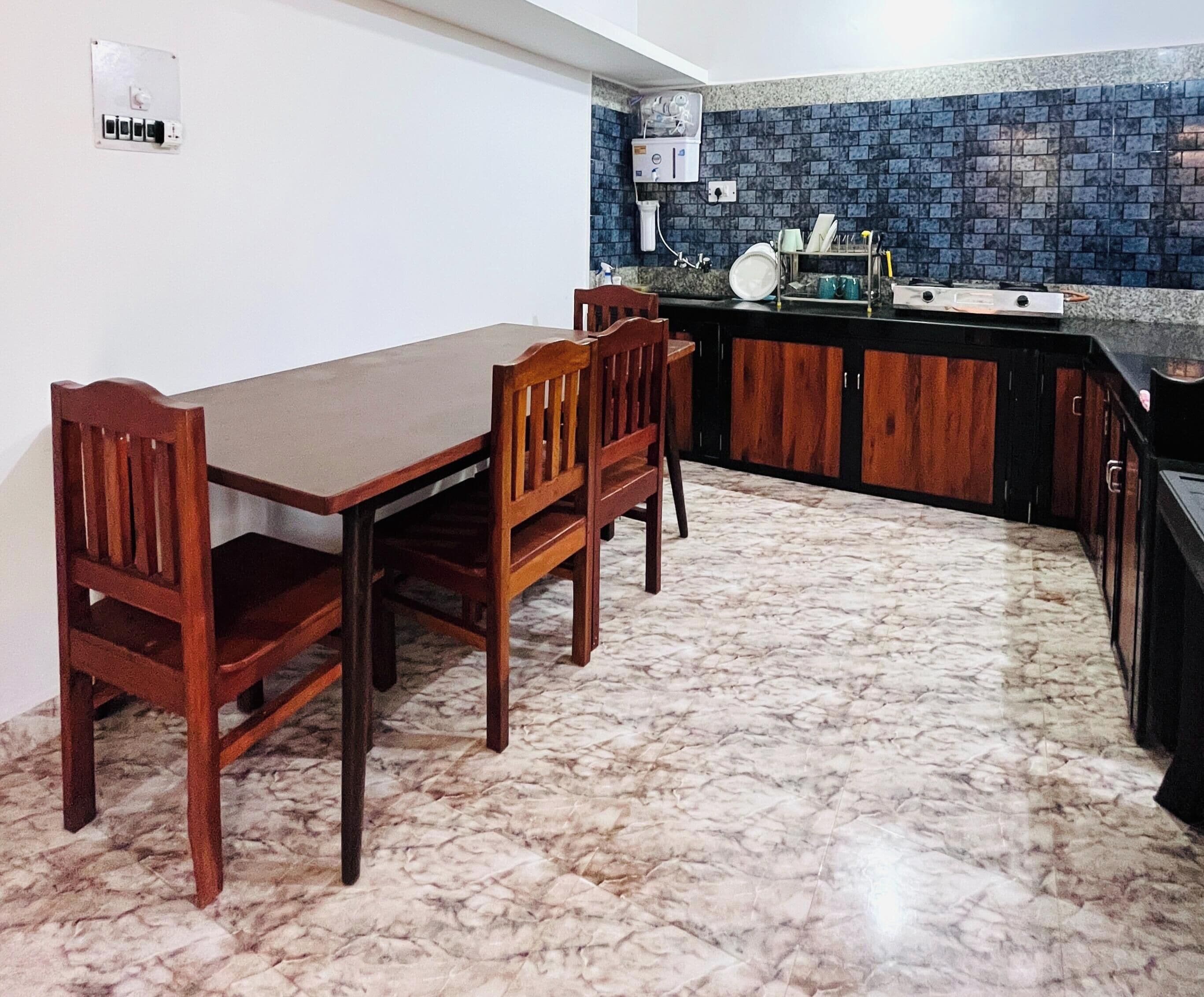 Una cocina con suelo de mármol, armarios de madera y una mesa de comedor con sillas.