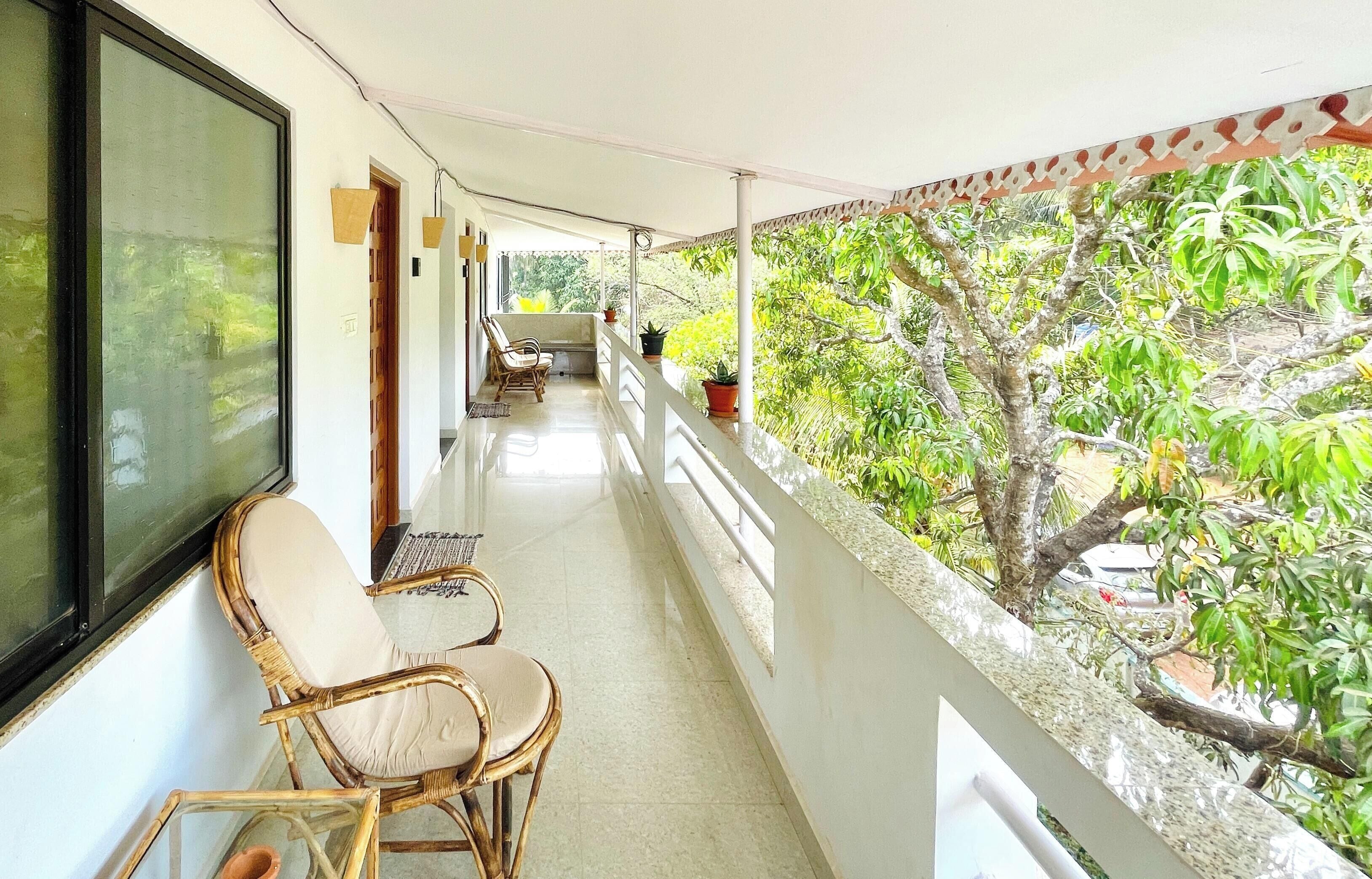 Ein Balkon mit Korbstühlen, einem kleinen Tisch und Topfpflanzen.