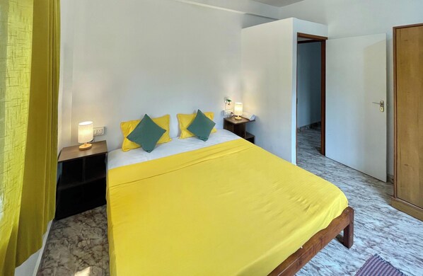 Une chambre d’hôtel avec un lit, une table de chevet, une lampe et une porte.